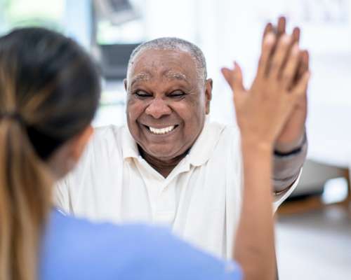 A patient and caregiver hold hands