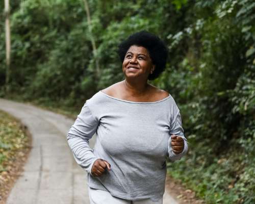 A woman jogs down a treelined pathway at the park