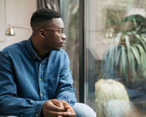 A young black man looks pensively out the window