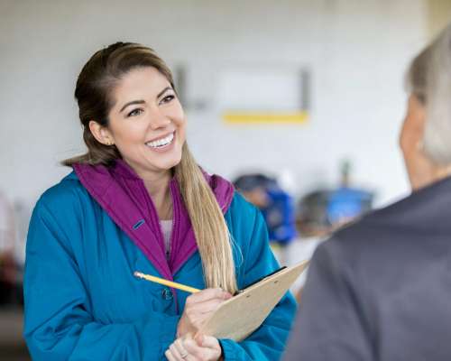 A woman smiles wide at someone she is speaking with.