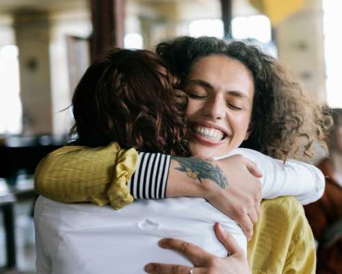 Two women smile wide as they embrace