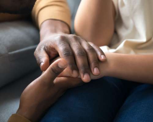 Many colored hands hold each other in a group