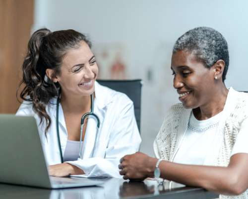 A provider and patient smile while talking in front of the computer