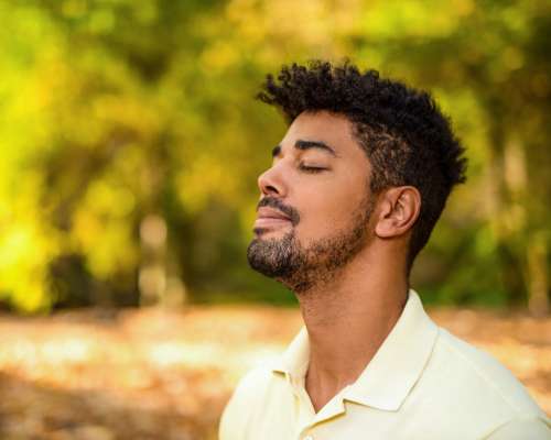 A young man faces the sun and closes his eyes