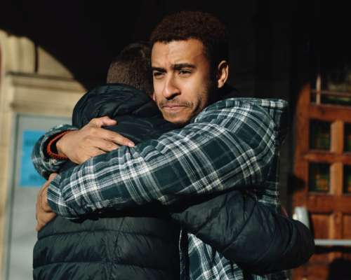 A father hugs his son at the door of a recovery home