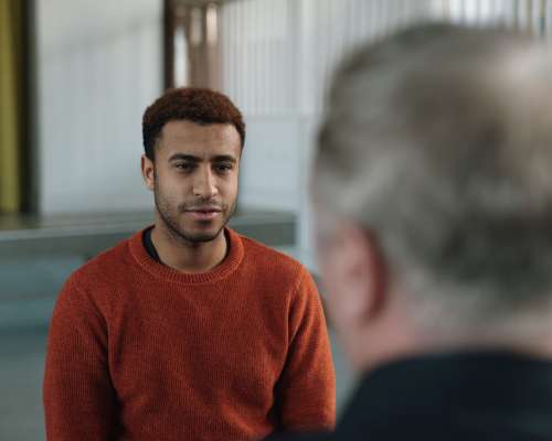 A man in a sweatshirt faces a group leader during an exercise