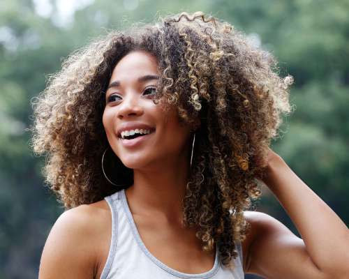 A young woman fluffs up her long hair and smiles