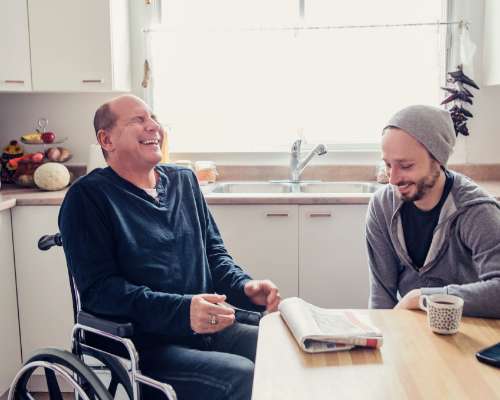 A man in a wheelchair laughs with an instructor