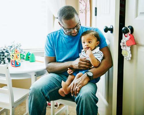 A man holds his infant in his arms while sitting at day care.