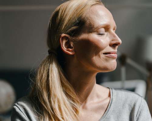 A woman's face, relaxing and absorbing the sunshine on her face.