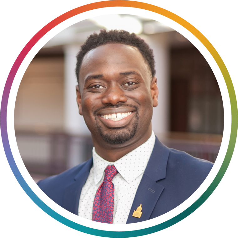 Q Williams smiles while wearing a suit